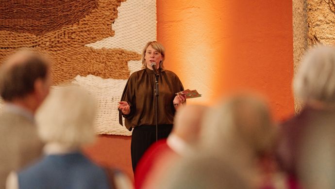 Vrouw in bruin shirt praat tegen het publiek