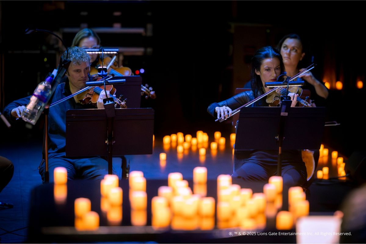 Foto van het concert met het scherm, orkest en kaarsen op de achtergrond