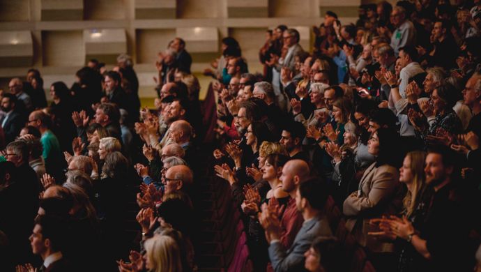 Publiek klapt en kijkt naar het podium