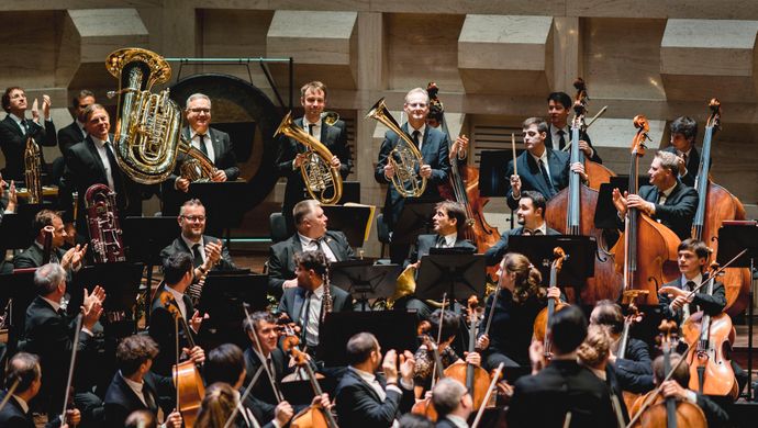 Orkestleden applaudiseren en kijken naar elkaar 