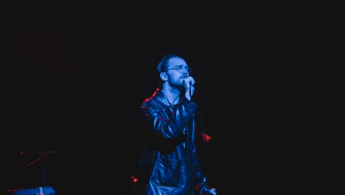 Sean Nicholas Savage singing and bathed in blue light
