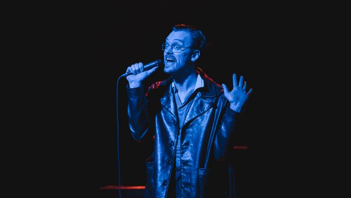 Sean Nicholas Savage singing and bathed in blue light