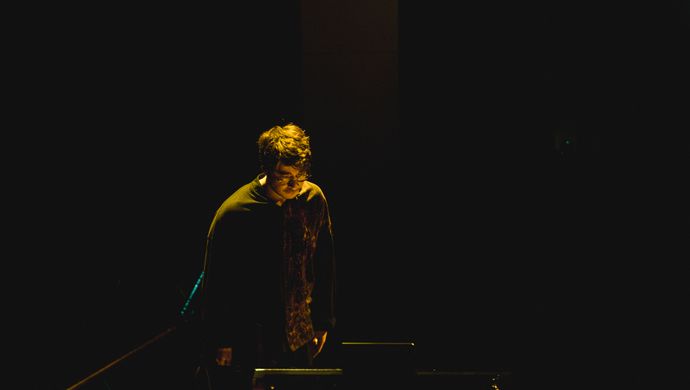Samson kijkt naar de piano terwijl hij wordt belicht door een schijnwerper