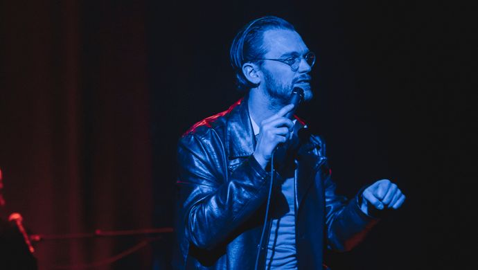 Sean Nicholas Savage singing and bathed in blue light