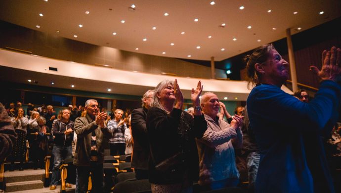 Publiek klapt en kijkt naar het podium