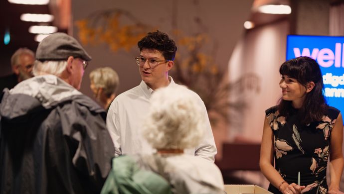 Vrouw met donker haar kijkt lachend naar man met witte blouse en bril