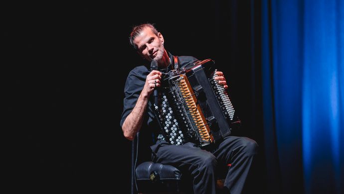 Accordeonist kijkt lachend naar het publiek
