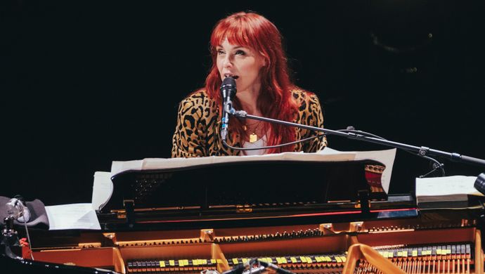 Wende sits at the piano and looks at the audience