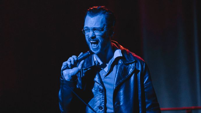 Sean Nicholas Savage singing and bathed in blue light