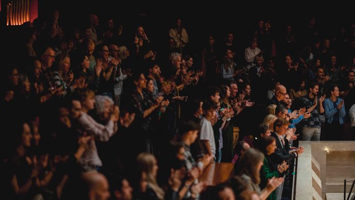Publiek klapt en kijkt naar het podium