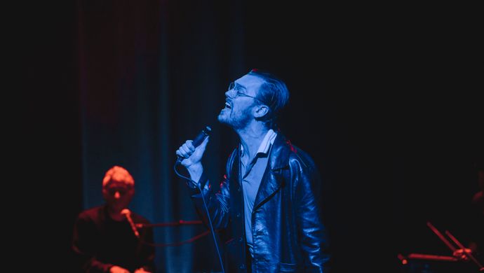 Singing Sean Nicholas Savage and a keyboardist in blue and red light.