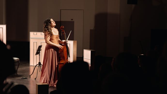 Alisa Weilerstein naast haar cello kijkend naar het publiek