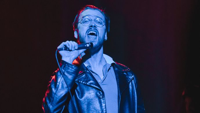 Sean Nicholas Savage singing and bathed in blue light