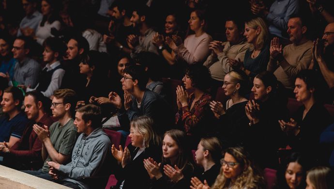 Publiek klapt en kijkt naar het podium