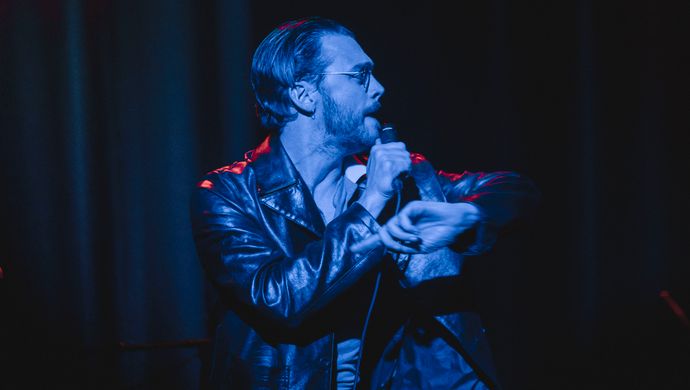 Sean Nicholas Savage singing and bathed in blue light