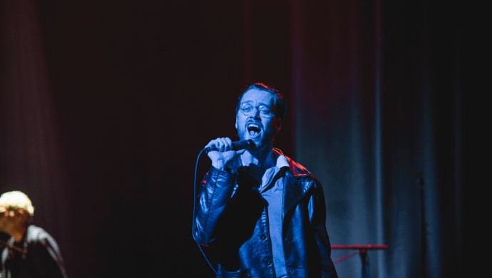 Singing Sean Nicholas Savage and a keyboardist in blue and white light.