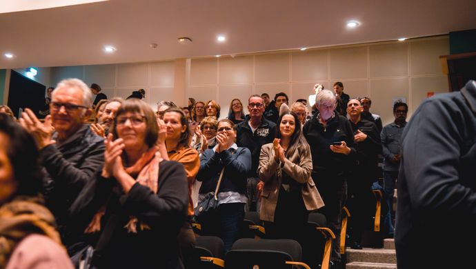 Publiek klapt en kijkt naar het podium