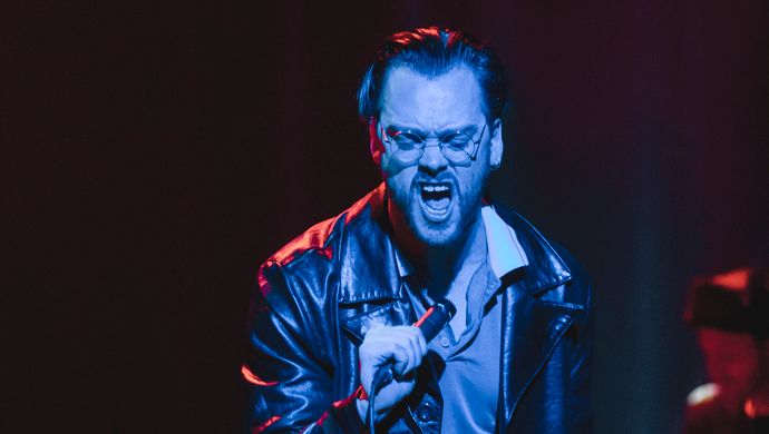 Singing Sean Nicholas Savage and drummer in blue and red light.