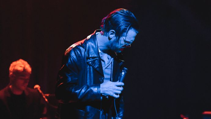 Singing Sean Nicholas Savage and a keyboardist in blue and red light.