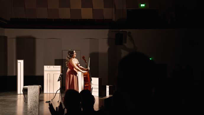 Alisa Weilerstein naast haar cello kijkend naar het publiek