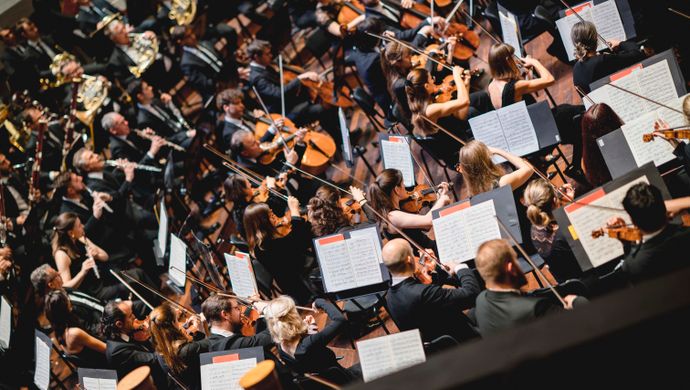 Orkestleden spelen en kijken naar de dirigent