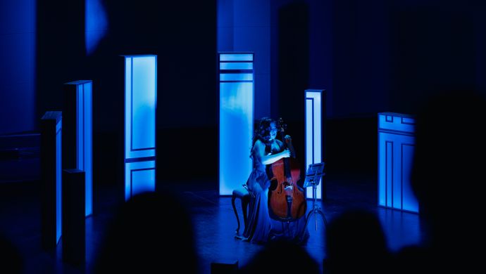 Alisa Weilerstein speelt de cello op het podium met blauw licht