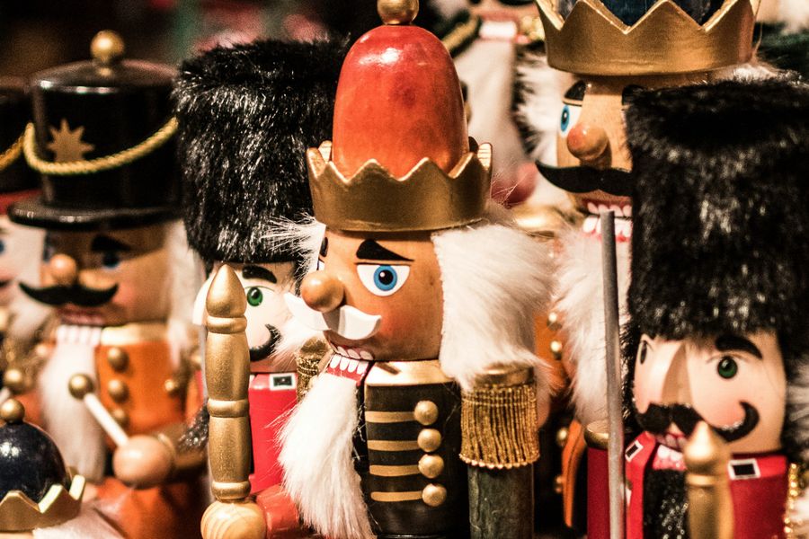 Close-up van een kleurrijke verzameling notenkrakers, met houten gezichten, felgekleurde uniformen en verschillende hoofddeksels, typisch voor kerstdecoratie.