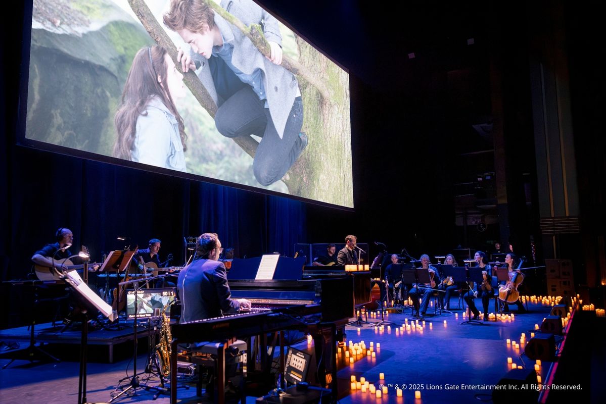 Foto van het concert met het scherm, orkest en kaarsen op de achtergrond