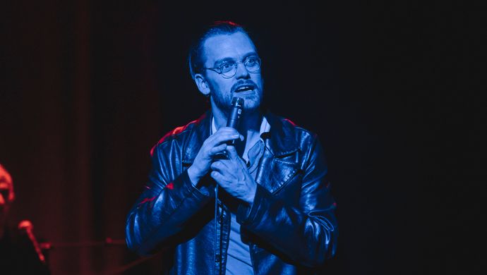 Sean Nicholas Savage singing and bathed in blue light