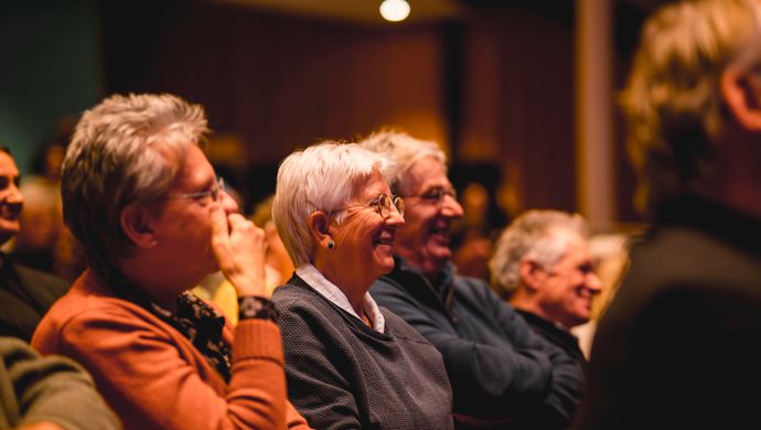 Publiek kijkt lachend naar het podium