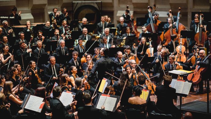 Orkestleden spelen en kijken naar de dirigent