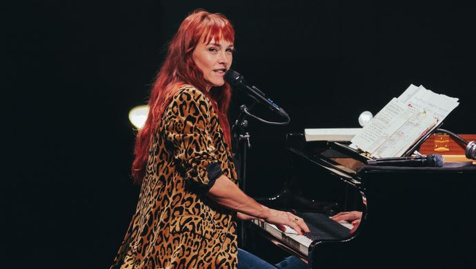 Wende sits at the piano and looks at the audience