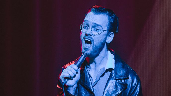Sean Nicholas Savage singing and bathed in blue light