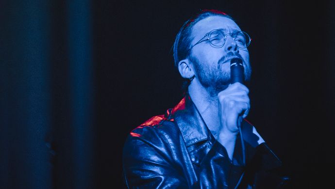 Sean Nicholas Savage singing and bathed in blue light