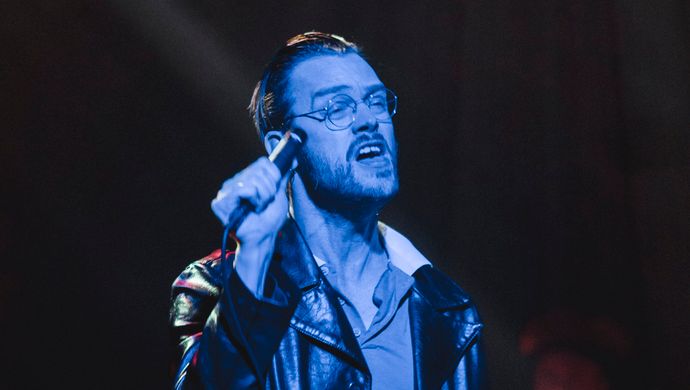 Sean Nicholas Savage singing and bathed in blue light