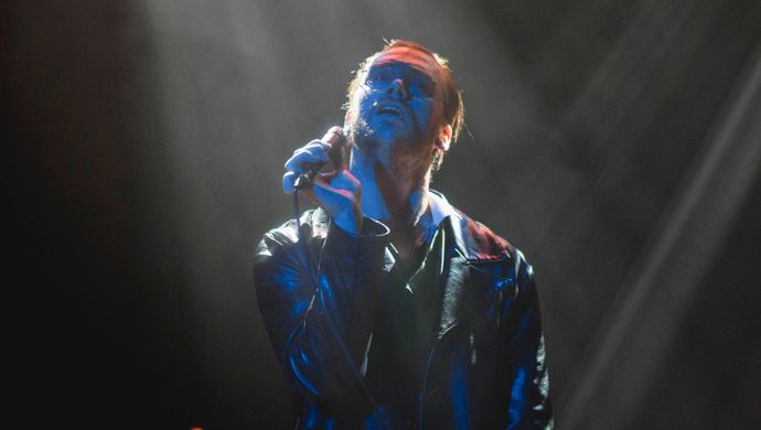 Sean Nicholas Savage singing and bathed in blue light, with a white spotlight in the background