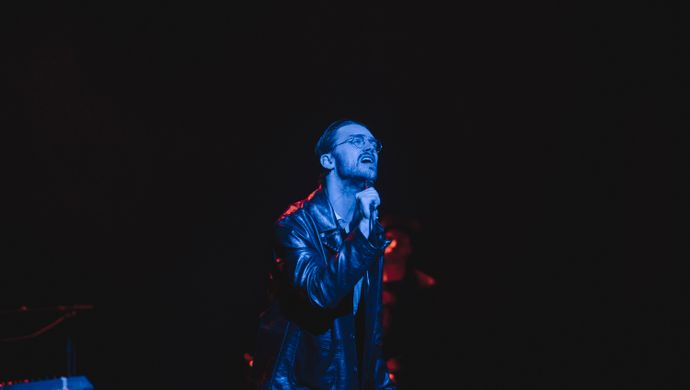 Sean Nicholas Savage singing and bathed in blue light