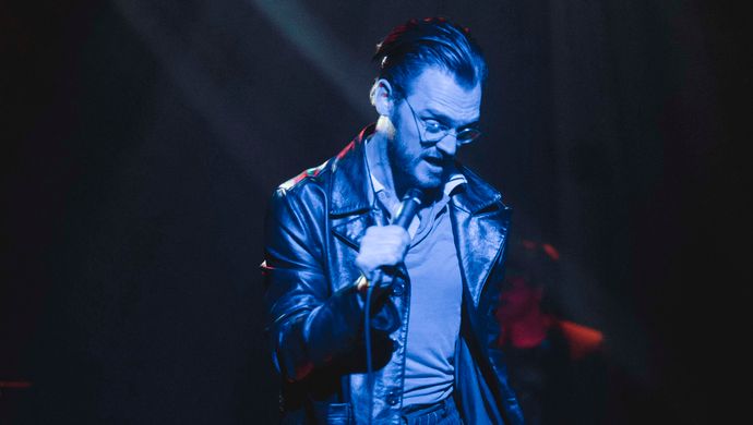 Sean Nicholas Savage singing and bathed in blue light