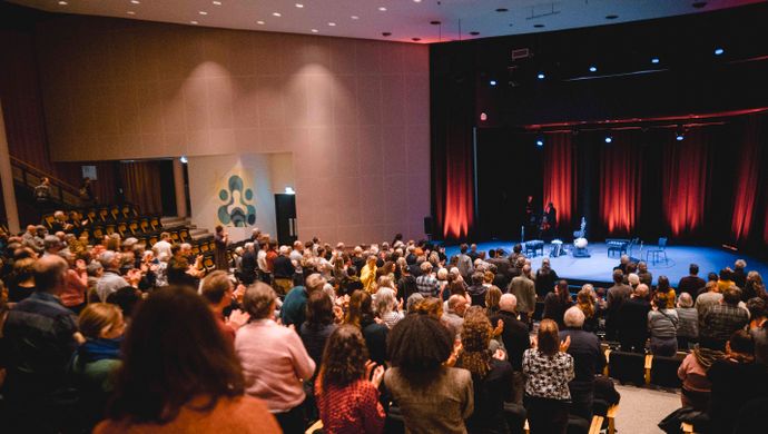 Publiek klapt terwijl de muzikanten het podium oplopen