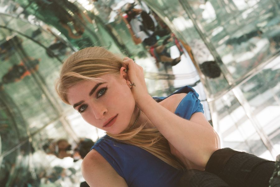 Kelly Moran, blonde vrouw met rode lipstick, zit in een spiegelruimte