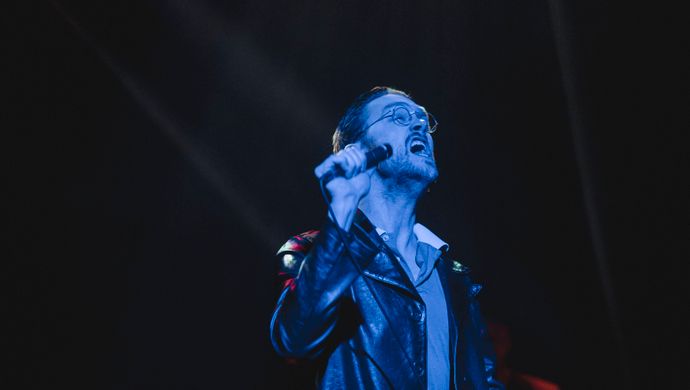 Sean Nicholas Savage singing and bathed in blue light