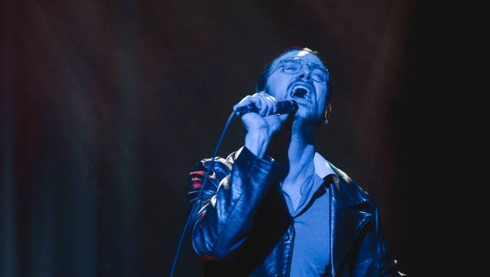 Sean Nicholas Savage singing and bathed in blue light