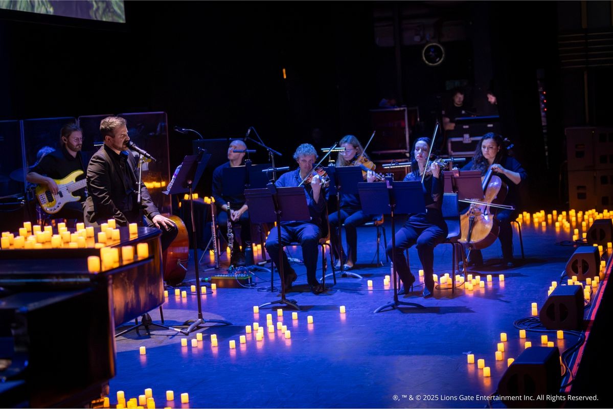 Foto van het concert met het scherm, orkest en kaarsen op de achtergrond