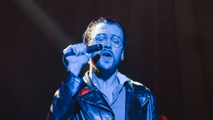 Sean Nicholas Savage singing and bathed in blue light