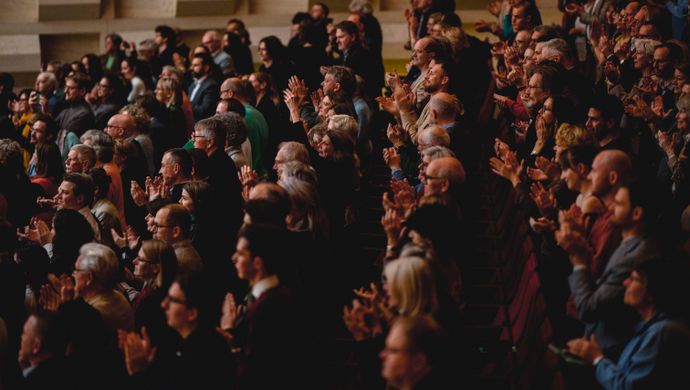 Publiek klapt en kijkt naar het podium