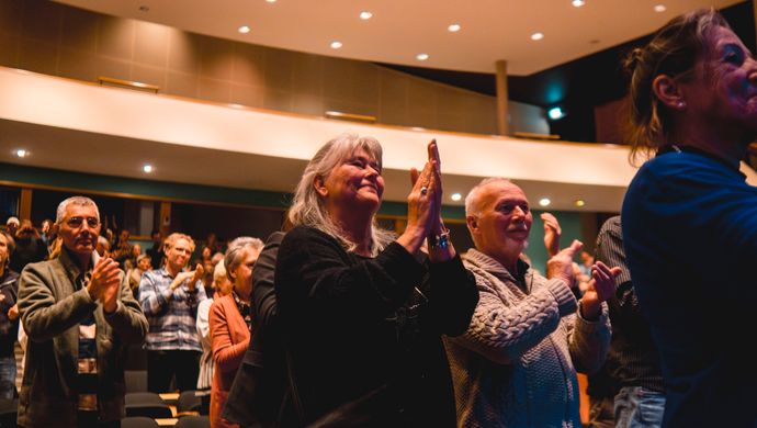 Publiek klapt en kijkt naar het podium