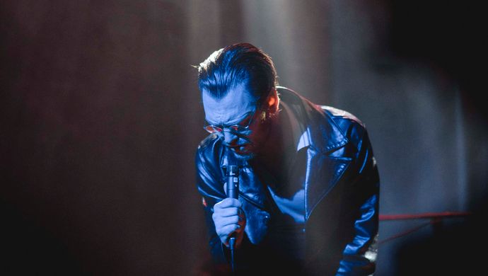 Sean Nicholas Savage singing and bathed in blue light, with a white spotlight in the background